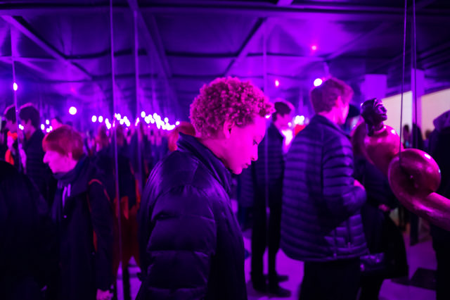 A person surrounded in purple light in a mirrored room.